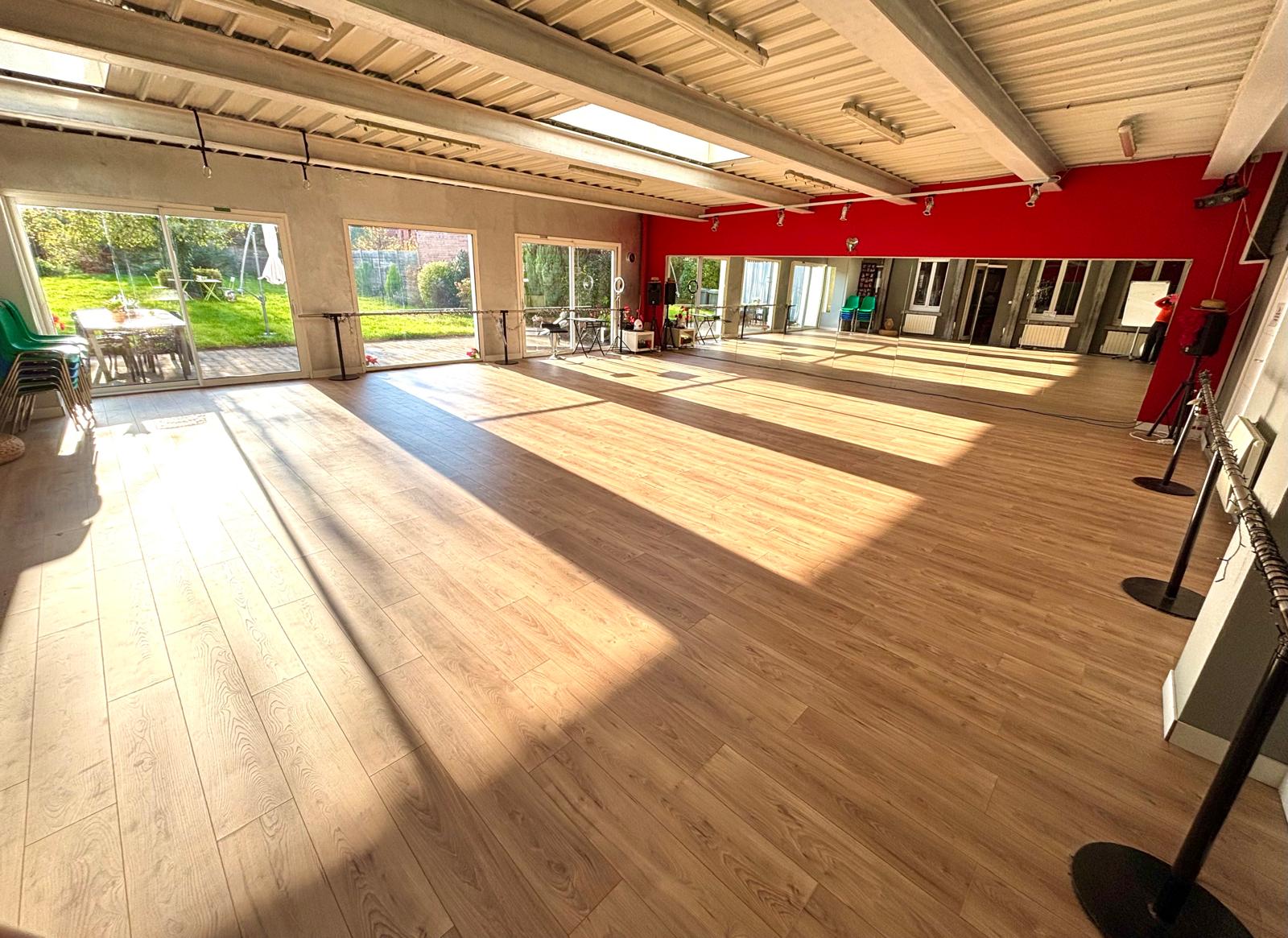 Grande salle lumineuse avec parquet, miroirs et vue sur le jardin